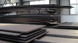 Stacks of heavy steel plates stored indoors for industrial fabrication use